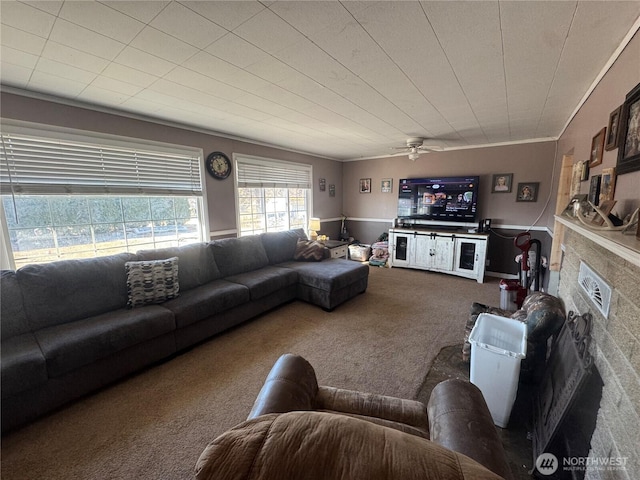 living room with ornamental molding, carpet, a fireplace, and a ceiling fan