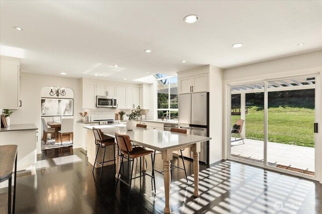 kitchen featuring backsplash, a breakfast bar area, recessed lighting, stainless steel appliances, and white cabinetry