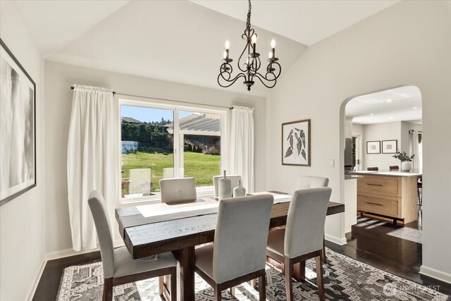 dining room featuring vaulted ceiling, dark wood-style floors, arched walkways, and baseboards