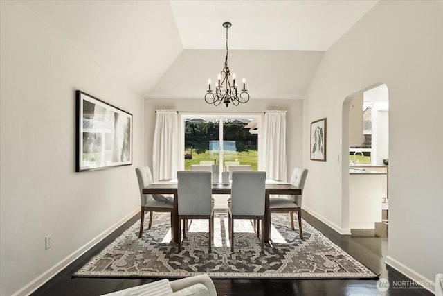 dining space with arched walkways, dark wood-style flooring, baseboards, and vaulted ceiling