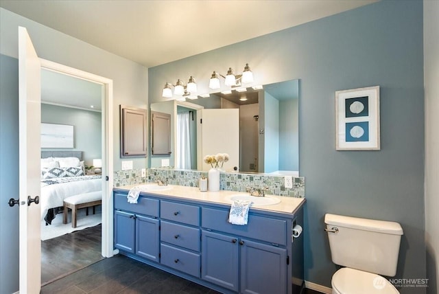 bathroom featuring ensuite bath, double vanity, a sink, toilet, and tasteful backsplash