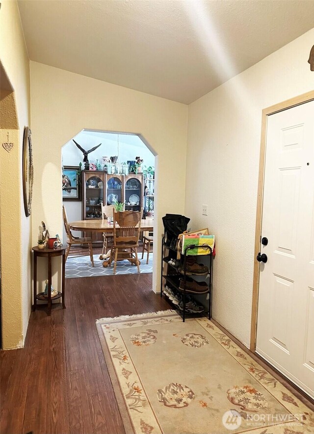 interior space with arched walkways and wood finished floors