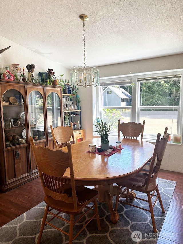 dining room featuring a notable chandelier, a textured ceiling, and dark wood-style flooring