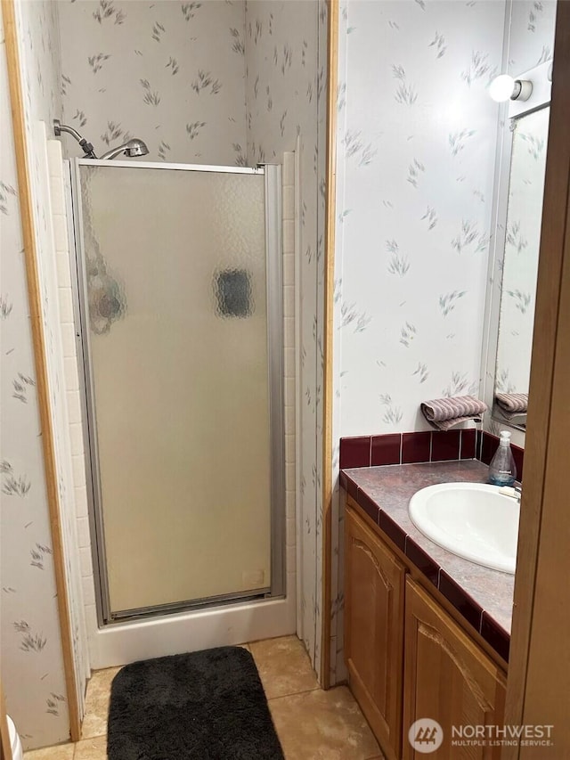 full bathroom featuring tile patterned flooring, a shower stall, vanity, and wallpapered walls