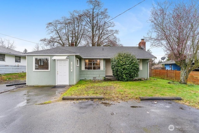 view of front of house featuring fence, roof with shingles, a front yard, a chimney, and crawl space