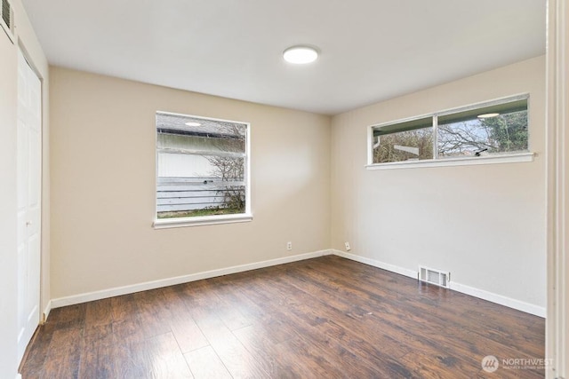 unfurnished room featuring visible vents, baseboards, and wood finished floors