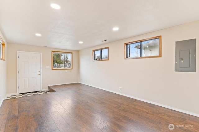 interior space with visible vents, baseboards, electric panel, recessed lighting, and dark wood-style floors