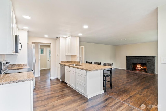 kitchen featuring a sink, stainless steel appliances, a breakfast bar area, and white cabinetry