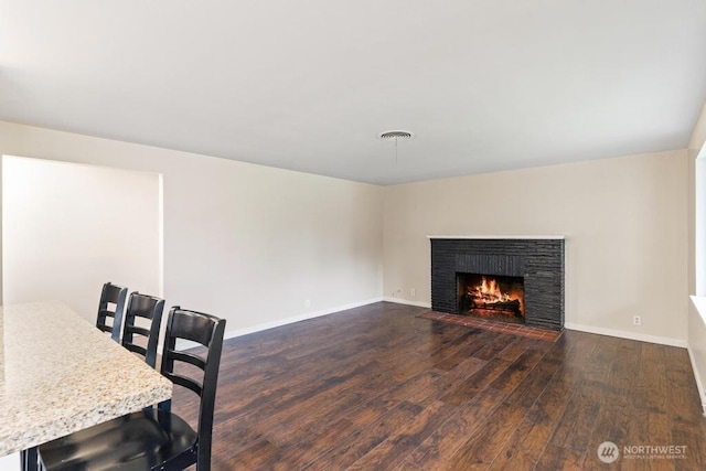 interior space with visible vents, baseboards, dark wood-type flooring, and a brick fireplace