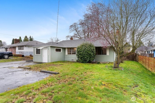 rear view of property with fence and a lawn