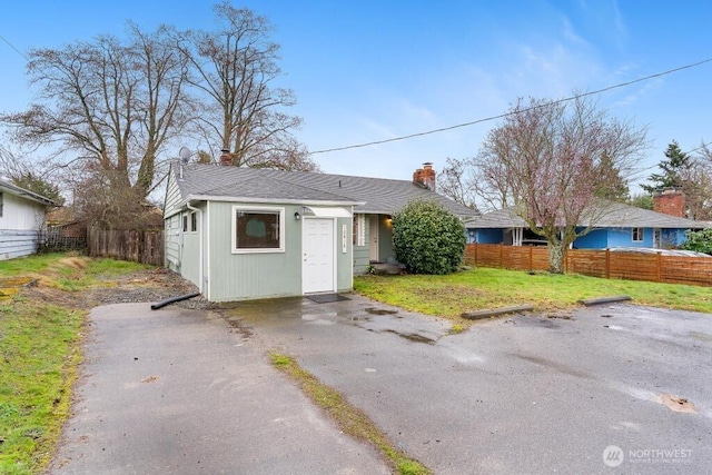 exterior space featuring a chimney, driveway, and fence