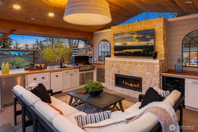 interior space with wooden ceiling, wooden walls, an outdoor stone fireplace, and vaulted ceiling