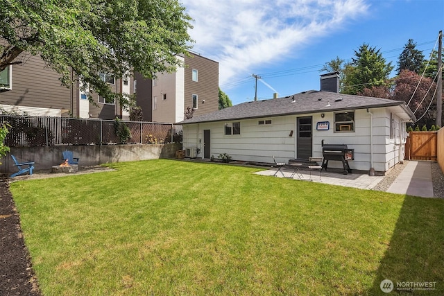 back of house featuring a patio, a fenced backyard, a lawn, roof with shingles, and a chimney