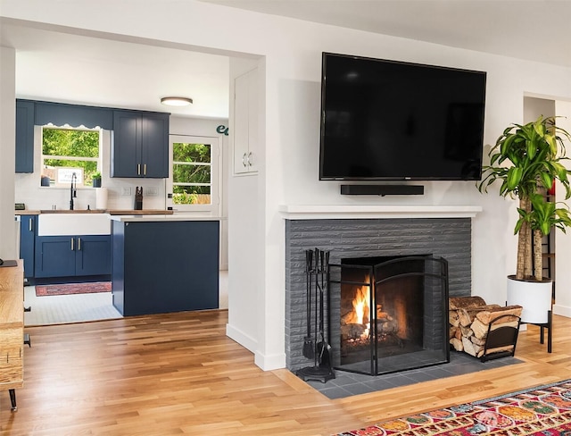 living room with light wood-style flooring, a fireplace, and baseboards