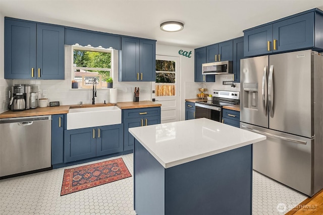 kitchen featuring appliances with stainless steel finishes, a sink, and blue cabinets