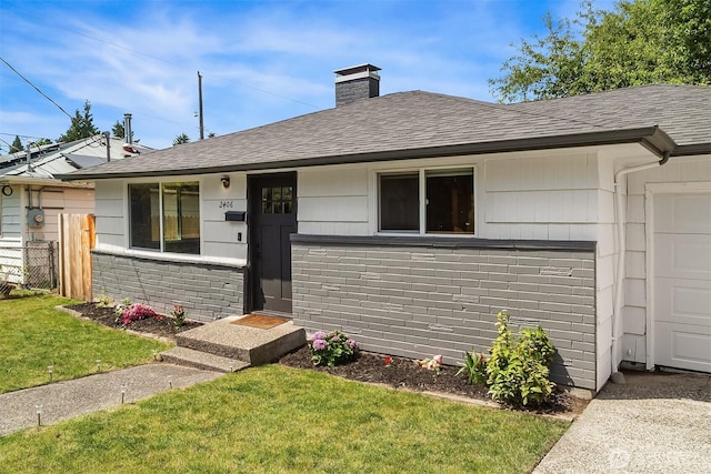 single story home featuring a shingled roof, brick siding, fence, and a front lawn