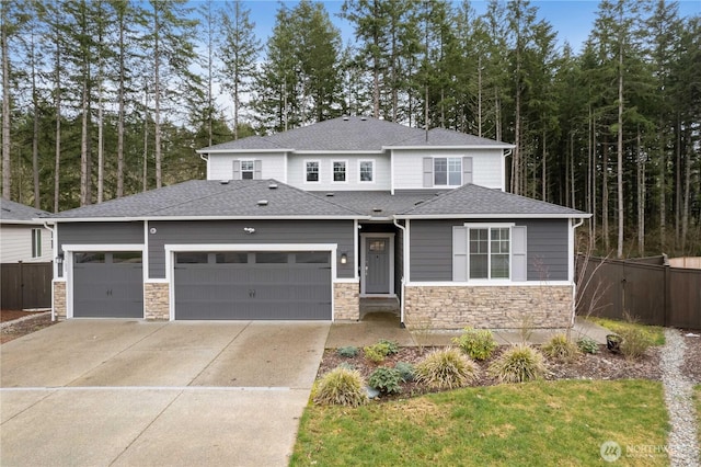 prairie-style house with an attached garage, a shingled roof, fence, and concrete driveway