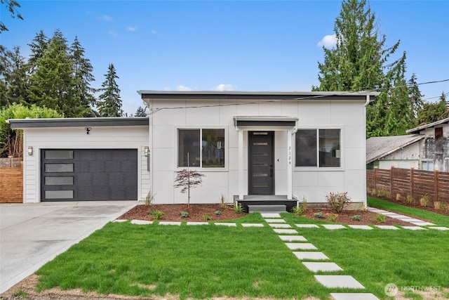 contemporary house featuring a garage, concrete driveway, fence, and a front lawn