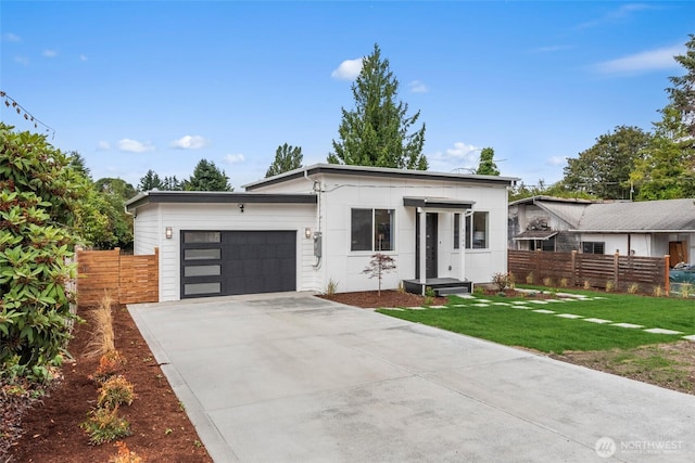 contemporary house featuring a garage, driveway, a front yard, and fence