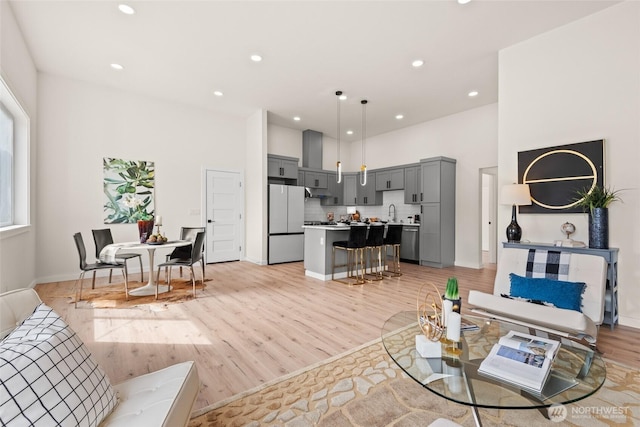 living area with light wood-style flooring, baseboards, and recessed lighting