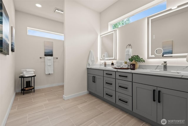 bathroom featuring double vanity, baseboards, visible vents, and a sink