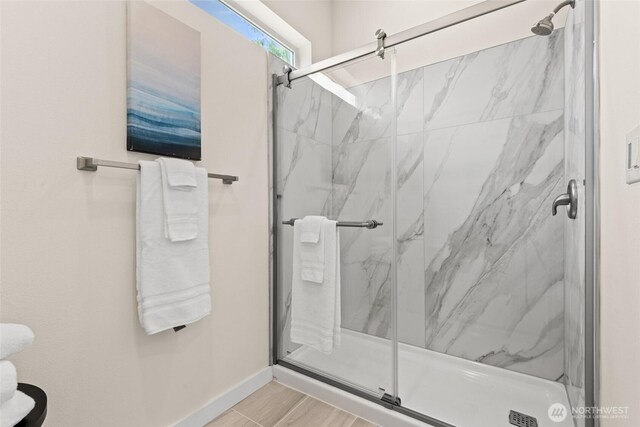 bathroom with baseboards and a marble finish shower