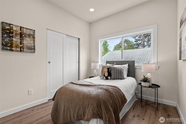 bedroom featuring a closet, baseboards, wood finished floors, and recessed lighting