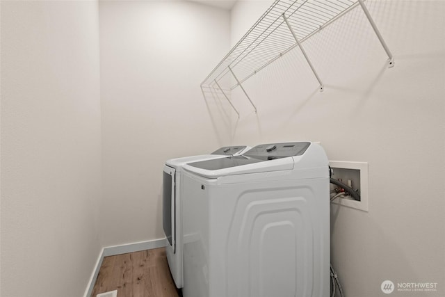 laundry room featuring laundry area, independent washer and dryer, light wood-style flooring, and baseboards