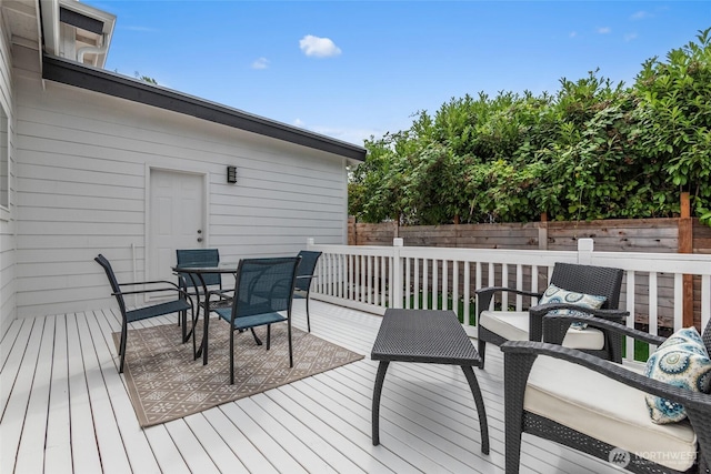 wooden terrace featuring outdoor dining area, fence, and an outdoor hangout area