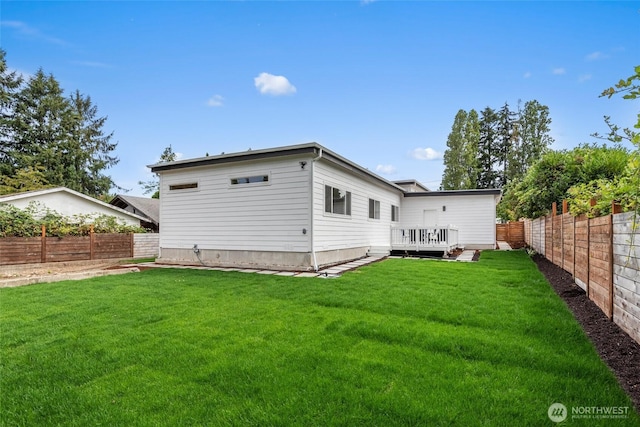 rear view of house featuring a fenced backyard, a lawn, and a deck