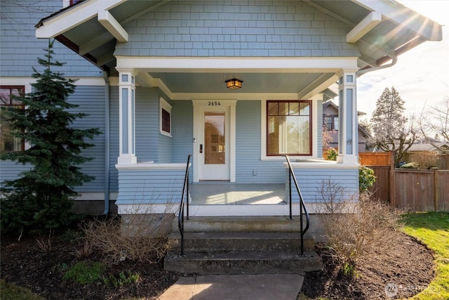 property entrance featuring covered porch and fence