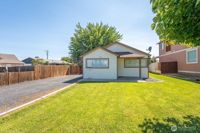 rear view of house with fence private yard and a lawn