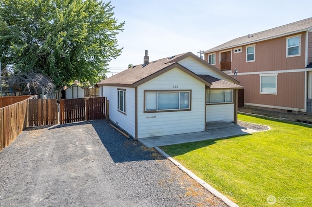 rear view of house featuring a lawn, a patio, an outbuilding, fence, and a shed