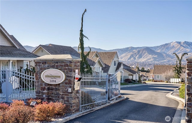 view of road with curbs, a residential view, a mountain view, and a gated entry