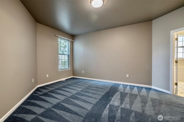 unfurnished room featuring baseboards and dark carpet