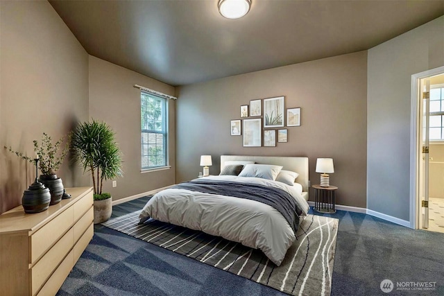 bedroom with dark colored carpet, baseboards, and ensuite bathroom