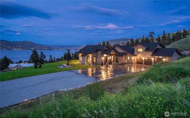 view of front of house featuring a front yard, gravel driveway, and a water and mountain view