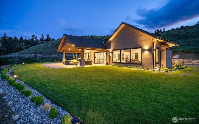 back of house featuring stucco siding, a lawn, a patio, and an outdoor hangout area