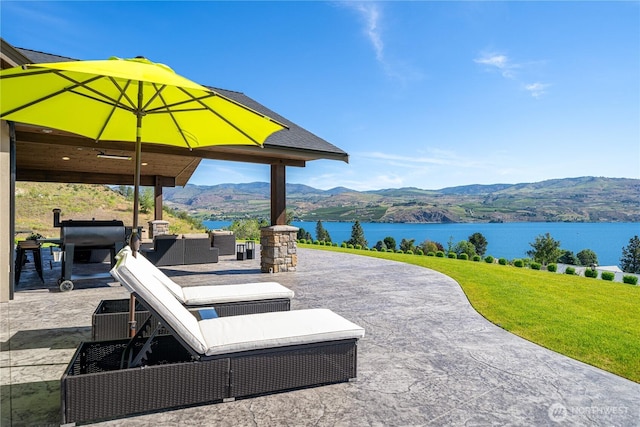 view of patio / terrace with an outdoor living space and a water and mountain view