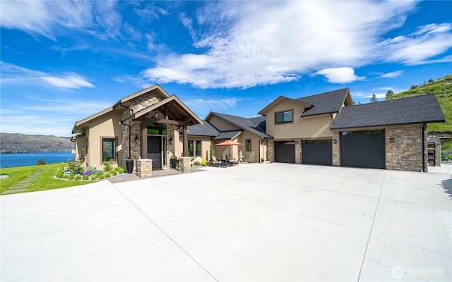 view of front of home with driveway, stone siding, a garage, and stucco siding