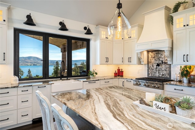 kitchen featuring lofted ceiling, decorative backsplash, a sink, and custom range hood