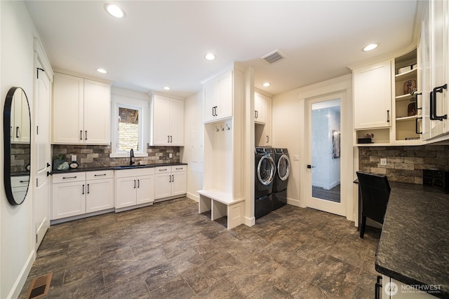 kitchen featuring a sink, visible vents, open shelves, washer and clothes dryer, and dark countertops