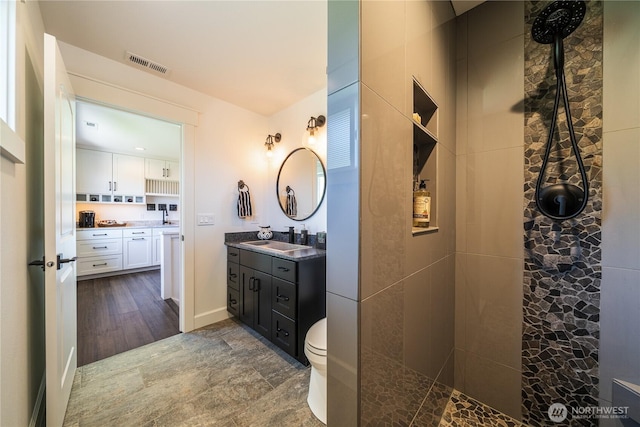 full bathroom featuring toilet, visible vents, a tile shower, and vanity