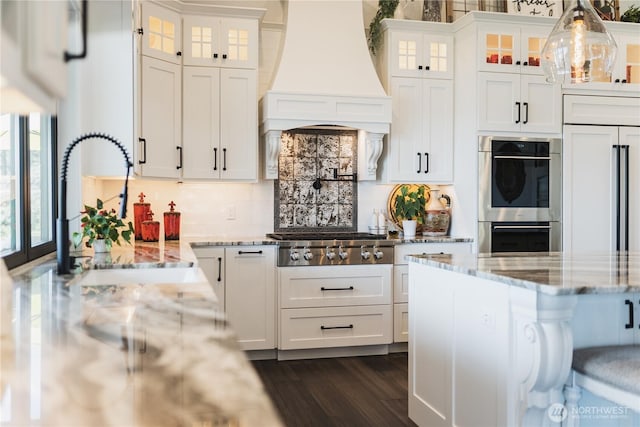 kitchen with glass insert cabinets, white cabinetry, custom exhaust hood, and stainless steel appliances