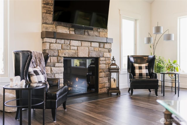 living area featuring a stone fireplace and wood finished floors