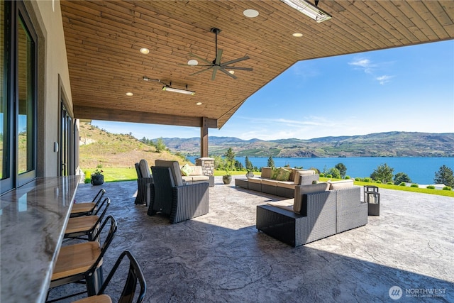 view of patio / terrace with ceiling fan, an outdoor living space, and a water and mountain view