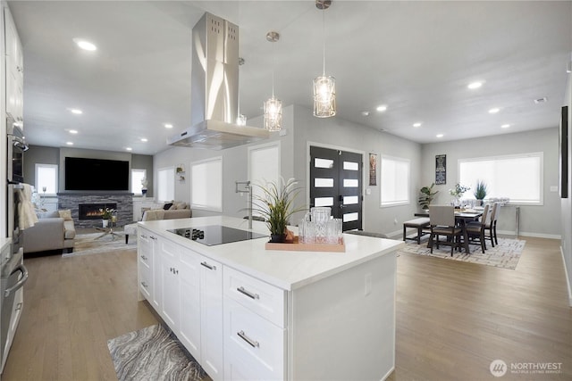 kitchen featuring light wood-style floors, black electric stovetop, white cabinets, and island range hood