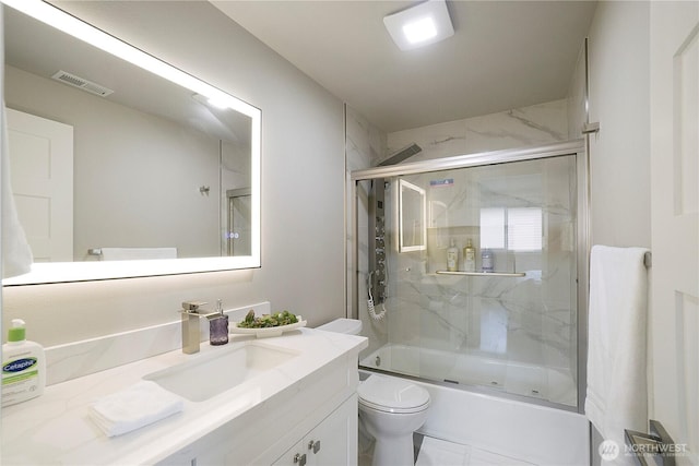 bathroom featuring visible vents, shower / bath combination with glass door, vanity, and toilet