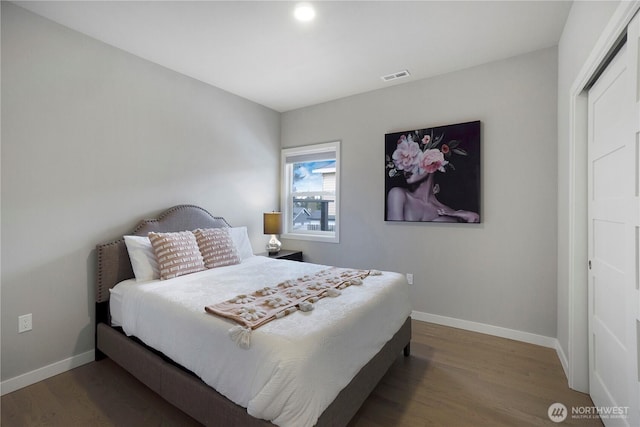 bedroom with wood finished floors, visible vents, and baseboards