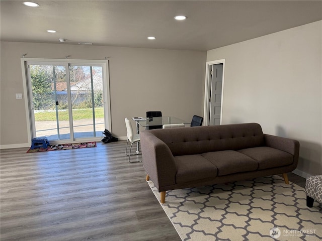 living area featuring baseboards, wood finished floors, and recessed lighting